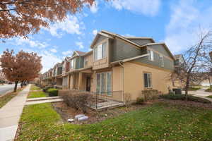 View of property exterior featuring stucco siding, a lawn, covered porch, and a residential view