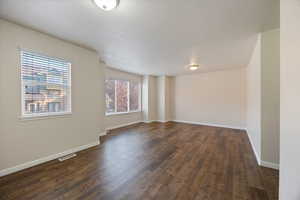 Spare room featuring dark wood-type flooring and baseboards