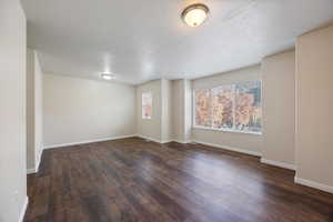 Spare room with dark wood-style flooring and baseboards