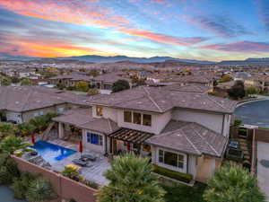 Back of house at dusk with stucco siding, a fenced backyard, a residential view, and a patio area