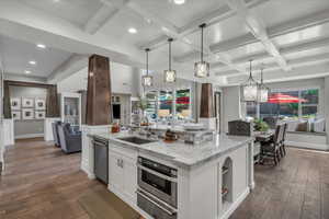 Kitchen featuring light stone countertops, white cabinets, coffered ceiling, dark wood-style flooring, and open floor plan