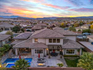 Back of property at dusk featuring a residential view, stucco siding, outdoor dining space, and a patio