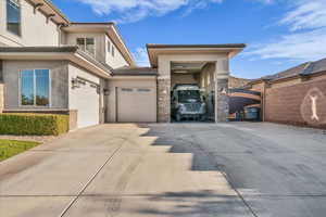 View of front facade with stucco siding, driveway, and a gate
