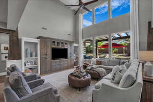 Living room with ceiling fan, a high ceiling, and wood finished floors