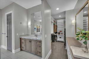 Full bath featuring a spacious closet, vanity, recessed lighting, and light tile patterned floors