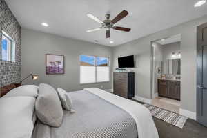 Bedroom featuring a ceiling fan, brick wall, connected bathroom, recessed lighting, and light carpet