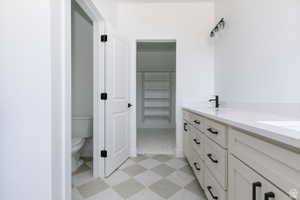 Bathroom with light flooring, double vanity, and a spacious closet