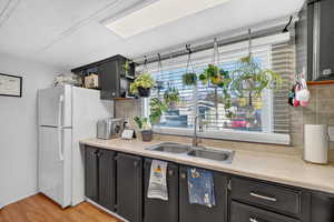 Kitchen with freestanding refrigerator, light countertops, tasteful backsplash, and light wood-style flooring