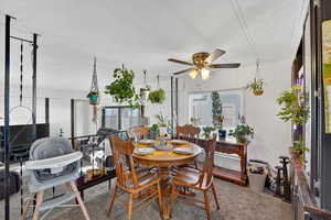 Carpeted dining area featuring ceiling fan