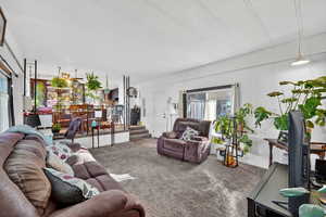 Carpeted living room featuring plenty of natural light and stairs