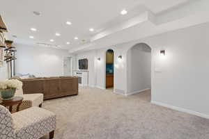 Living area with arched walkways, recessed lighting, and light carpet