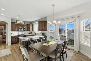 Dining room with a chandelier, light wood-type flooring, arched walkways, and recessed lighting
