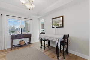 Dining area featuring arched walkways, light wood-type flooring, ornamental molding, and a chandelier