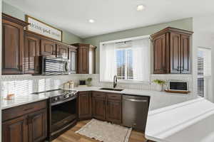 Kitchen with appliances with stainless steel finishes, dark brown cabinets, light wood-style flooring, tasteful backsplash, and recessed lighting