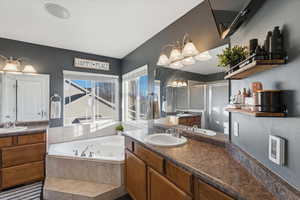 Full bath with two vanities, a stall shower, and a tub with jets