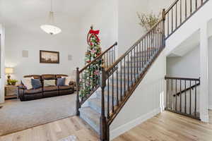 Stairway with a towering ceiling and wood finished floors