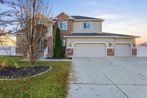 Traditional home featuring concrete driveway, stucco siding, an attached garage, and brick siding