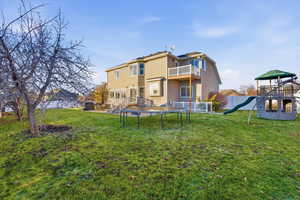 Back of property featuring a playground, a trampoline, stucco siding, a balcony, and a patio
