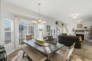 Dining space featuring a large fireplace, light wood finished floors, and a chandelier