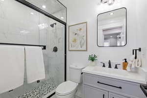 Bathroom featuring a marble finish shower, vanity, and recessed lighting
