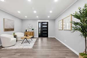 Foyer entrance with crown molding, wood finished floors, and recessed lighting
