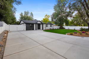 View of front of house with a gate, a fenced backyard, driveway, and an attached garage