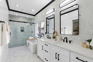Bathroom with a soaking tub, light marble finish flooring, crown molding, double vanity, and a marble finish shower