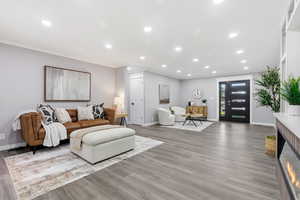 Living room featuring crown molding, recessed lighting, and light wood-style floors