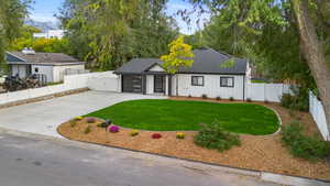 View of front of house with a shingled roof, concrete driveway, a fenced backyard, board and batten siding, and a gate