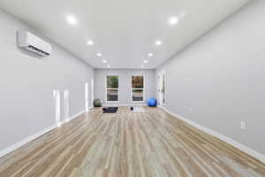 Exercise room featuring recessed lighting, light wood-style flooring, and a wall mounted air conditioner