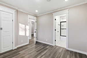 Unfurnished bedroom featuring a closet, wood finished floors, recessed lighting, crown molding, and ensuite bath