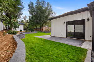 Fenced backyard with an outdoor structure and a patio area