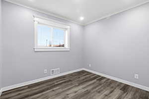 Empty room with crown molding, dark wood-type flooring, and recessed lighting