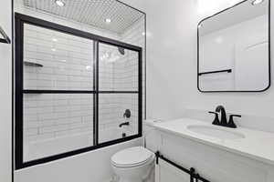 Bathroom featuring vanity, bath / shower combo with glass door, and recessed lighting