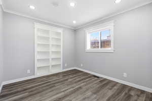 Spare room with dark wood-style floors, crown molding, and recessed lighting