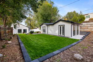 Rear view of house with french doors, board and batten siding, a fenced backyard, and an outbuilding