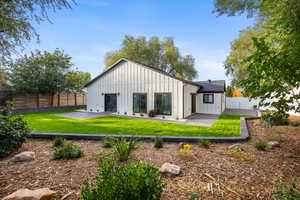 Rear view of property featuring board and batten siding, a fenced backyard, and a patio