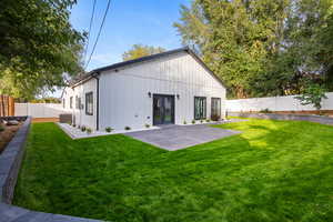 Rear view of house featuring a fenced backyard, french doors, and board and batten siding