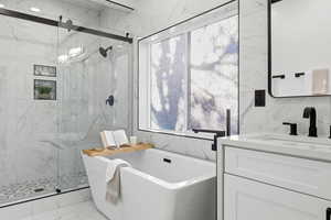 Full bathroom featuring light marble finish floors, a soaking tub, vanity, and a marble finish shower