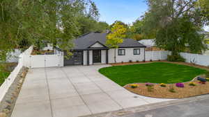 View of front facade with a gate, roof with shingles, a fenced backyard, driveway, and a garage