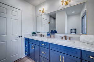 Full bath with double vanity, a marble finish shower, and light wood-style flooring