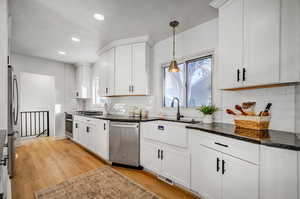 Kitchen featuring white cabinets, dark stone counters, appliances with stainless steel finishes, recessed lighting, and light wood-style floors