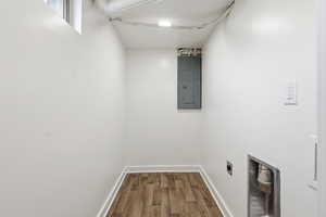 Washroom with electric panel, dark wood-style floors, and hookup for an electric dryer