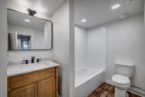 Bathroom with vanity, dark wood finished floors, shower / bath combination, and recessed lighting