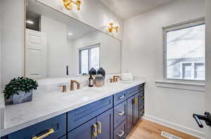 Full bathroom featuring double vanity and light wood-style floors