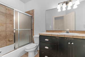 Bathroom with vanity, combined bath / shower with glass door, and light tile patterned flooring