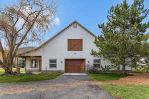 View of front of property with a front lawn, a garage, driveway, and covered porch