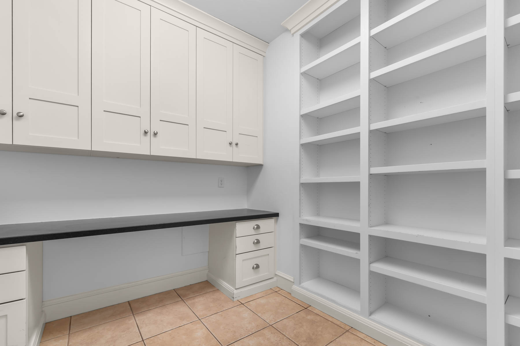 Unfurnished office featuring light tile patterned flooring and built in desk