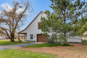 View of side of home with a yard, a garage, and asphalt driveway