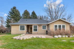 Back of property featuring a patio area, a yard, and roof with shingles